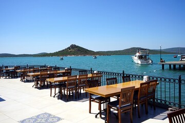 Terrasse eines Restaurant mit Tischen und Stühlen und Blick auf das Meer im Sommer bei...