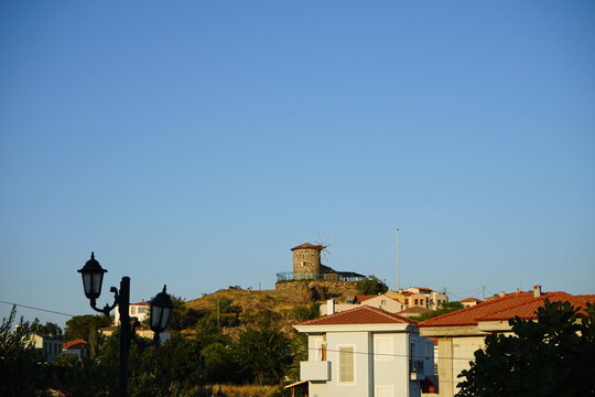 Alte Windm&uuml;hle aus Naturstein auf einem H&uuml;gel vor blauem Himmel im Licht der untergehenden Sonne in Cunda bei Ayvalik am &Auml;g&auml;ischen Meer in der Provinz Balikesir in der T&uuml;rkei