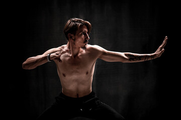 Asian man fighter practices martial arts on black background. Kung fu and karate pose. In addition, discipline, concentration, meditation, etc. concepts