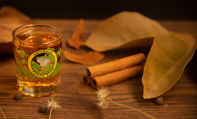 Costa Rican rum served in a shot glass with a frog image, on a wooden table with dry leaves