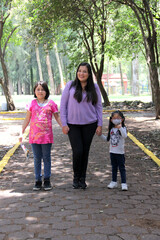 Obraz premium Single and divorced Latin mom and daughters walk in the park outdoors alone spend quality family time on summer vacation or weekend 