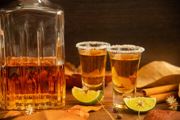 Tequila, shots with autumn decoration, with dry leaves on wooden table