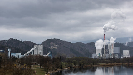 The heavy gray sky over thermal power plant smokestacks that blow out smoke and smog, burning coal polluting the air