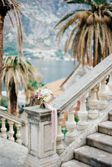 Wedding bouquet stands on a balustrade overlooking the sea and mountains