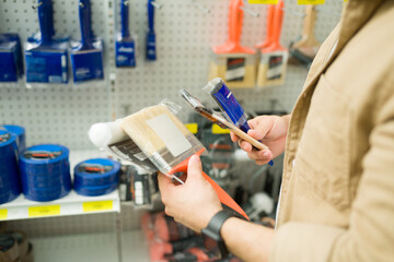 Customer deciding what paint brush to buy at the store