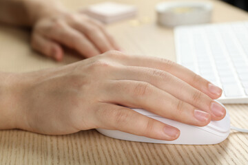 Woman using wired computer mouse at wooden table, closeup