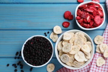 Bowls and dried fruits on turquoise wooden table, flat lay. Space for text