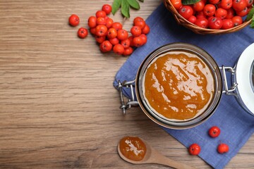 Flat lay composition with delicious rowan jam and berries on wooden table. Space for text