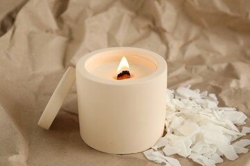 Burning soy candle and wax flakes on crumpled kraft paper