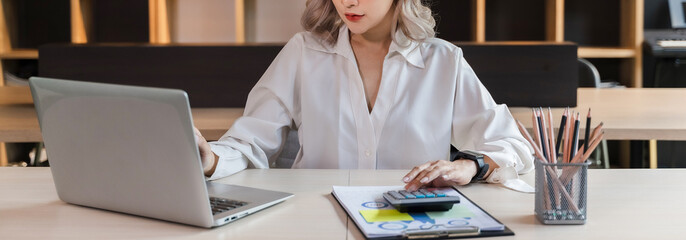 Beautiful Asian portrait businesswoman manager smile workingin office with a laptop in the modern office sitting online marketing financial communication.