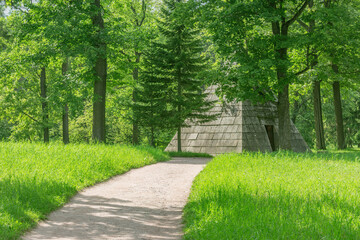 Narrow walkway and stone pyramid in the summer park.