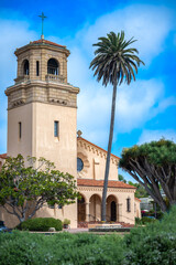 2022-08-23 A SPANISH STYLED CHURCH ENTRANCE WITH A TOWER AND GREEN FOLIAGE WITH A NICE LIGHT BLUE SKY AND CLOUDS IN LA JOLLA CALIFORNIA - obrazy, fototapety, plakaty