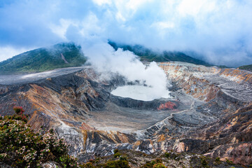 horizontal photo of the Poas volcano from a distance in Costa Rica, a wide shot of a volcano spewing steam surrounded by stones. © Rodrigo Ojeda