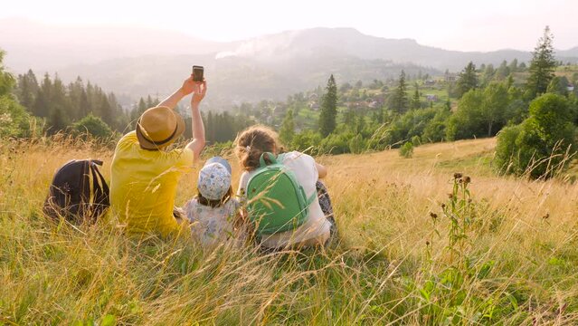 Young parents caucasian baby travel mountain vacation time together holiday park phone photo. Caucasian family outdoors young family taking photo family mountain phone mobile mountain walking together