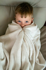 Cold season, a frozen preschool boy covered with warm plaid spend time at home, , winter family...
