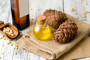 pine nut oil on bottle on white wooden table with cones