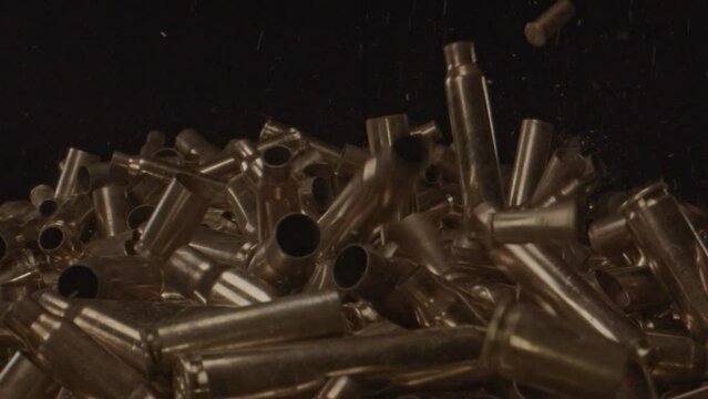 Stunning slow motion of spent shell casings falling on a pile of bullet shells.