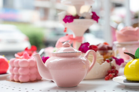Abundance of close up pink sweet desserts, teapot on table. Opening of new cafe or bakery, fresh tasty food assortment