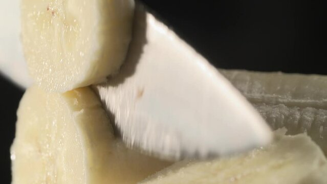 utting a banana on a black stool and a black background with a chef's knife, high quality sexy close-up, food porn