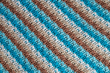 close-up of grandma's crocheted or knitted blue, tan, brown, and white striped blanket, this blanket makes you think of grandma's house, it is cozy and warm