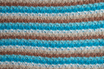 close-up of grandma's crocheted or knitted blue, tan, brown, and white striped blanket, this blanket makes you think of grandma's house, it is cozy and warm