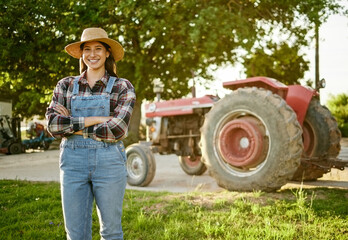 Farm, agriculture and tractor with a young woman farmer standing outside in the farming industry....