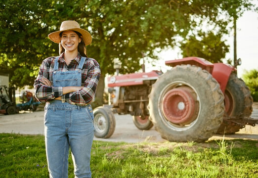 Farm, Agriculture And Tractor With A Young Woman Farmer Standing Outside In The Farming Industry. Sustainability, Organic And Eco Friendly Agricultural Harvest During Summer Or Spring Harvest Season