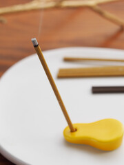 黄色いお香たてに立てられたスティックタイプのお香