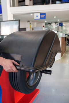 m&atilde;o de um mec&acirc;nico segurando a tampa do equipamento de balancear rodas 