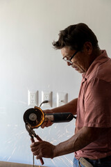 man using angle grinder, cutting a screw, friction sparks, clamping screw with tweezers...