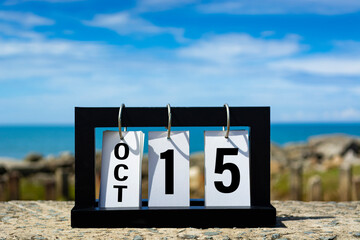 Oct 15 calendar date text on wooden frame with blurred background of ocean.