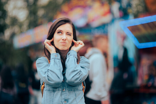 Unhappy Woman Bothered by Loud Music at Noisy Outdoors Funfair. Stressed woman frustrated and annoyed with the unbearable noise
