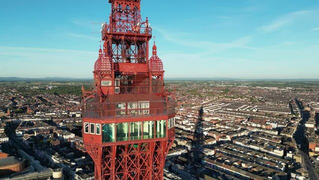 Aerial drone flight around the observation deck of Blackpool Tower showing the glass windows and floor and panning around to show the coastline and rooftops below