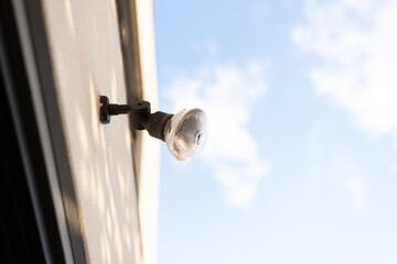 An outdoor security flood light on the wall against sky background.