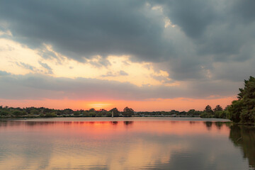 Pink and grey sunset reflection along Woodlawn Lake in San Antonio