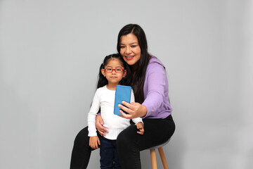 Single divorced Latina mom and daughter use cell phone to video call, take selfies, play video games, and shop online