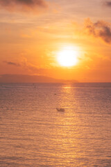 Beautiful cloudscape over the sea, sunrise shot. Lonely boats. Vung Tau beach, Vietnam with beautiful yellow sunrise sky, sun and clouds in orange and blue tones.