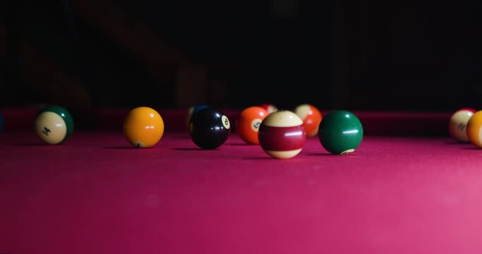 Slow motion Man hits cue ball and breaks ball rack on the pool table.