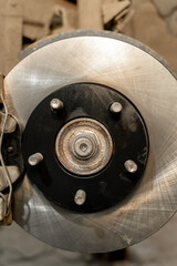Disc brake on a car, brake disc replacement in a car service. The rim is removed, exposing the rotor and caliper. Close-up.