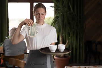 upset female waiter holding serving tray in restaurant with bad tips