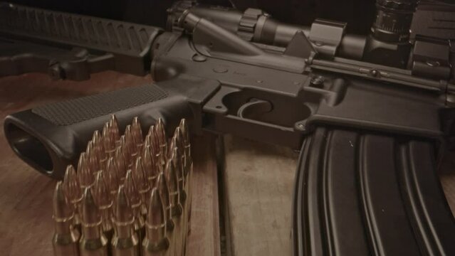 High angle dolly out from loaded AR-15 assault rifle with a small amount of ammunition in the foreground