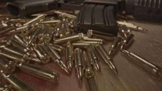 Stunning macro dolly out of AR-15 assault rifle lower with magazine laying on top of live .223 ammo