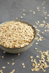 Dry Organic Rolled Oats in a Bowl on a gray background, side view.