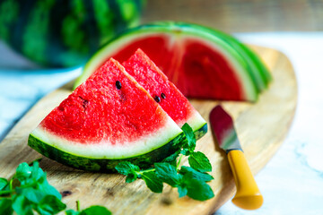 Fresh watermelon slices on a wooden board with fresh mint, copy space, selective focus