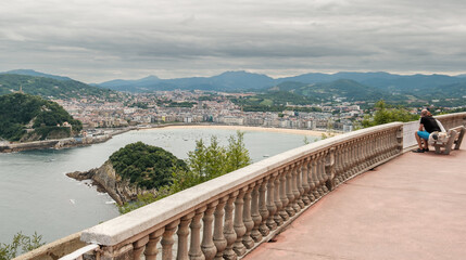 Obraz premium TOW PEOPLE ENJOYING BEAUTIFUL VIEWS OF LA CONCHA BEACH ON A CLOUDY DAY