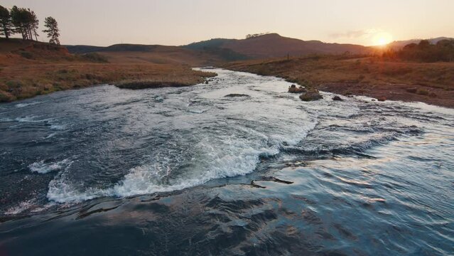 Rapid river flows in Brazilian mountains at sunset