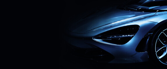 Detail on one of the LED headlights super car in blue tone on black background	