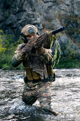 Close-up photo of a mercenary military sniper during a sabotage mission behind enemy lines - he stands knee-deep in the river and aims at the enemy.