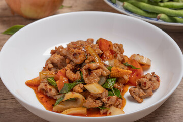 Pork stir fried in chili paste with tomatoes and onions in a white dish
