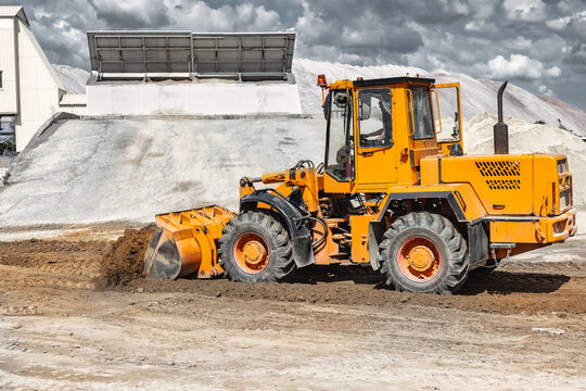 A large front loader pours sand into a pile at a construction site. Transportation of bulk materials. Construction equipment. Bulk cargo transportation. Excavation.